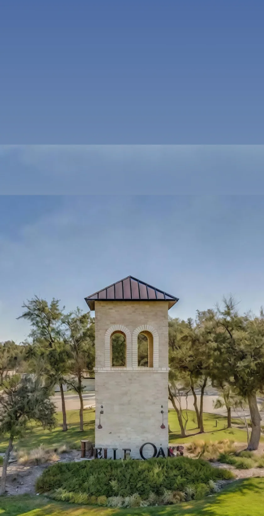 The limestone entrance monument and curving road at Belle Oaks