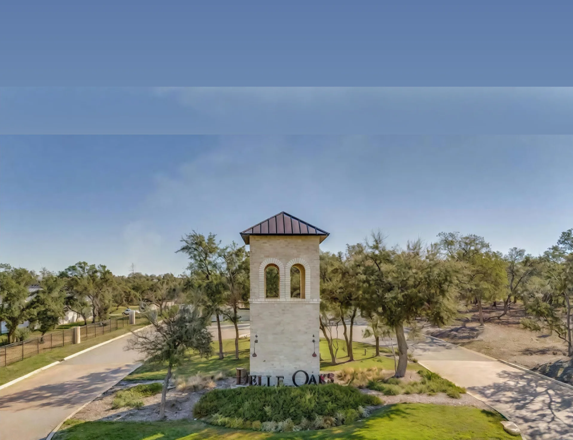 The limestone entrance monument and curving road at Belle Oaks